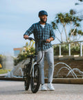 Person walking with a fat tire bike near a park fountain.