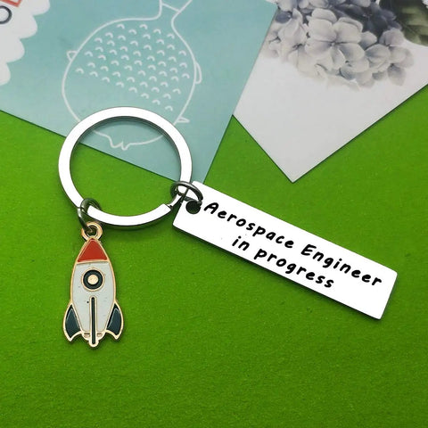 Funny Aerospace Engineer Keychain Gift For Graduation And Appreciation with rocket charm on green surface