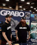 Grab On Pro Electric Suction Cup Lifter demonstration at a trade show with two men showcasing the portable heavy-duty tool.