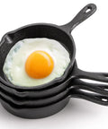 Stack of Four Pack Mini Cast Iron Skillets 4 Inch With Double Drip Spouts, Stove Oven Grill Safe, with a fried egg on top