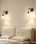 BANGANMA 2-Pack Black Farmhouse Hardwired Wall Sconces Crystal for Bathroom mounted above a bed with beige pillows and wall light.