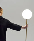 Person holding Luna LED Floor Lamp Dope Modern Tall Light For Living Rooms And Home Offices With Frosted Glass Globe Mid Century Style