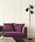 Modern living room with Lexie 67 Inch Floor Lamp With 3 Pivoting Heads In Matte White Finish And Antique Brass Accents next to purple sofa.