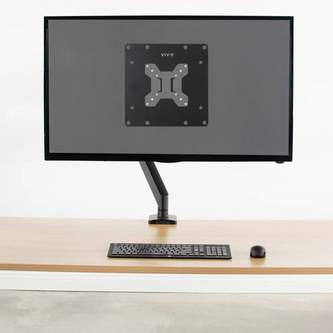Built Tough VESA Adapter Bracket For TVs And Monitors Max 42 Inches mounted on a desk with keyboard and mouse.