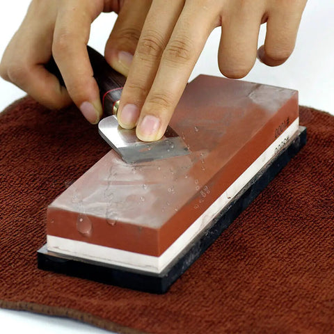 Pro Grade Knife Sharpening Stone Kit With 400 1000 And 3000 8000 Grit Wet Whetstones being used on a knife