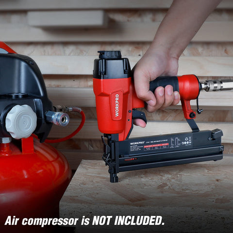 Hand holding 18 Gauge Pneumatic Brad Nailer And Crown Stapler 2 In 1 Nail Gun connected to air compressor on wood surface
