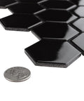 Dope Glossy Black Porcelain Hex Mosaic Tile, 2 inch pieces, showing high sheen finish next to a coin for size reference, mesh-mounted.