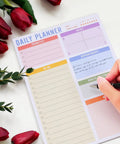 Person writing on a daily planner with red flowers, Portable Memo Pad Notebook For Daily Use With No Residue After Tearing.