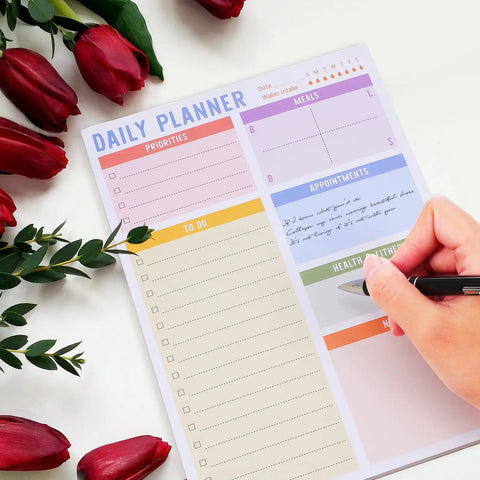 Person writing on a daily planner with red flowers, Portable Memo Pad Notebook For Daily Use With No Residue After Tearing.
