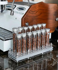 Single Dose Coffee Bean Storage Tubes, Glass And Aluminum Vials, Fourteen Piece Set With Acrylic Board on kitchen counter.