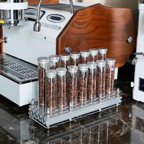 Single Dose Coffee Bean Storage Tubes, Glass And Aluminum Vials, Fourteen Piece Set With Acrylic Board on kitchen counter.