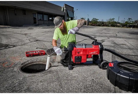 Thinking Process: worker using cordless drain cleaner with auto cable feed at outdoor sewer opening
