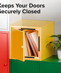 Yellow cabinet with door open displaying books, demonstrating magnetic tape with adhesive backing; plant beside for decor.