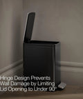 Black Stainless Small Trash Can With Foot Pedal And Quiet Close Lid 1.6 Gallon 6 Liter Fingerprint Resistant Stainless Steel Waste Bin placed against wall showcasing hinge design preventing wall damage.