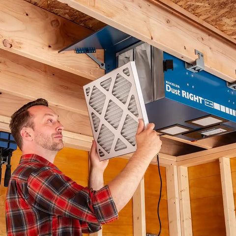 Man installing a filter in a Compact Ceiling Air Filtration Unit With Heavy Duty Triple Stage Filters for Tight Garages.