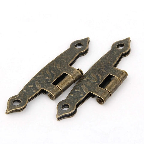 Close-up of two antique bronze cabinet hinges, 65x34mm, 4 holes, vintage luggage style hardware for furniture renovation.