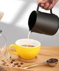 20 Oz Milk Frother Pitcher For Espresso And Latte Art Pen For Foam Stainless Steel Steaming Cup With Nonstick Coating Black Coffee Frothing Cup For Cappuccino And Milk Foam pouring milk into yellow cup