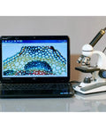 Portable Student Microscope with Slide Preparation Kit next to laptop displaying cell structure, LED illumination visible