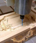Blue-coated 3-flute carbide CNC router bit, 1/8 in diameter, 1/4 in shank, installed in spindle cutting wood.