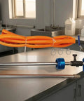 Adjustable Coolant Mixer For Cutting Fluid Dispensing with metal control assembly, orange hose kit on workbench.
