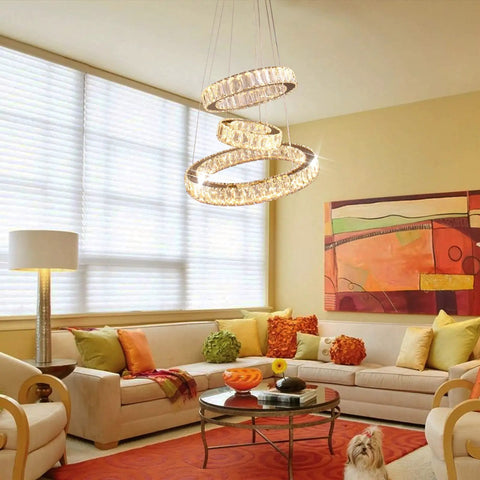 Dimmable Dope Modern LED Chandelier With Three Ring Pendant Lights hangs in a bright living room above a glass coffee table.