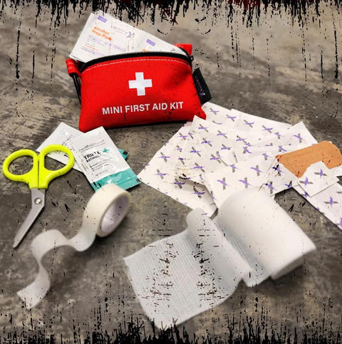 Red mini first aid kit pouch with zipper; scissors, bandages, tape, and gauze visible.