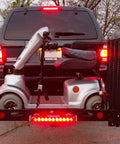 Rear view of hitch-mounted cargo carrier with LED tail lights carrying a mobility scooter on a SUV
