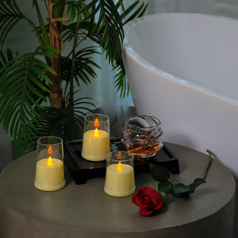 Ivory Flameless Taper Candles With Remote And Timer, set of three, on table with red rose, next to white bathtub