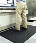 Person standing on Built Different And Tough As Nails Anti Fatigue Mat With Heavy Duty Diamond Texture in a workshop setting.