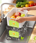 Five Pack Fridge Storage Containers with Removable Colanders, upper drain over lower storage, in kitchen sink with fruits.