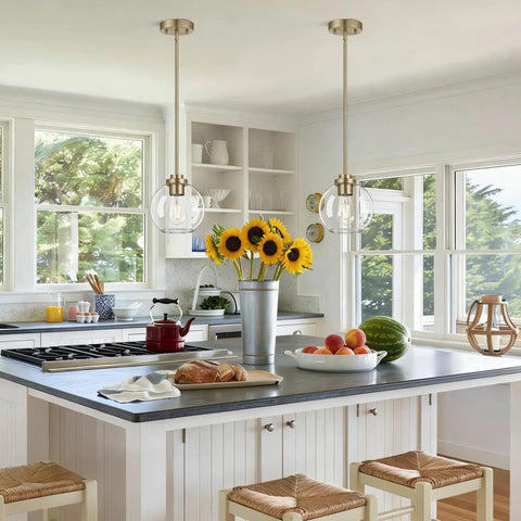 MQMQA 2 Pack Globe Pendant Lights, Mid Century Brass Pendant Light Fixtures over a kitchen island with sunflowers and fruit.