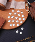 Top view of silver pyramid flatback studs for leathercraft (200pcs) scattered on leather and cork.