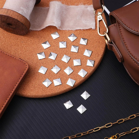 Top view of silver pyramid flatback studs for leathercraft (200pcs) scattered on leather and cork.
