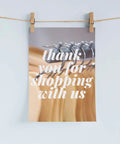 Thank you for shopping with us card hanging on a clothesline with clothespins.