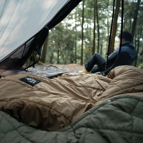 Ultralight Sleeping Quilt For Backpacking And Hammock Camping, 40 Degree Warmth With Footbox, seen inside a tent with trees outside.