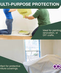 Two people painting a wall; a Cotton Duck Canvas Drop Cloth 12 By 15 Feet For Painting And Diy Projects covers furniture.