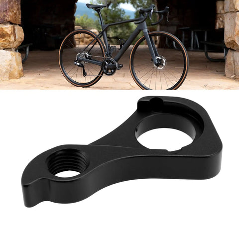Rear Derailleur Hanger CC1117 CNC Compatible With Giant Revolt Series Bikes next to a black bike on a stone floor