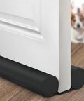 Heavy Duty Adjustable Door Draft Stopper And Weather Stripping Seal Blocks Those Stubborn Drafts Dust And Pesky Bugs While Keeping Your Place Snug All Year Round Black under a white door on hardwood floor.