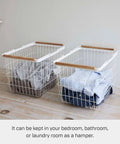 Two Tosca Laundry Basket With Wooden Handles Medium 11 Inch Steel And Wood Durable Rectangular Laundry Hamper With Ample Interior Space For Clothes 6 Gallons 23 Liters filled with laundry on a wooden floor.