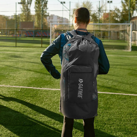 Person carrying Extra Large Mesh Ball Bag For Soccer, Basketball, Volleyball, Football And More on a sports field