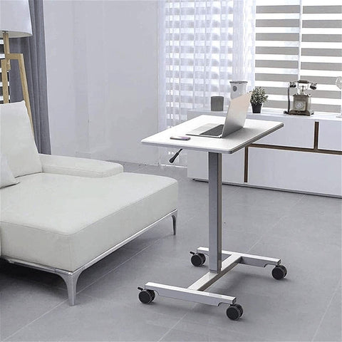 Fully Adjustable Rolling Laptop Stand With Rugged Aluminum Frame Convertible Standing Desk Tray beside a white couch in a modern living room.
