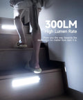 Under cabinet lights illuminating stairs, showcasing 300LM brightness. Focus keyword: Two Pack Under Cabinet Lights With 2000mAh Rechargeable Battery, 62 LED Wireless Motion Sensor Night Light For Kitchen Hallway Closet, Four Modes, Stick On Magnetic Design For Easy Setup.