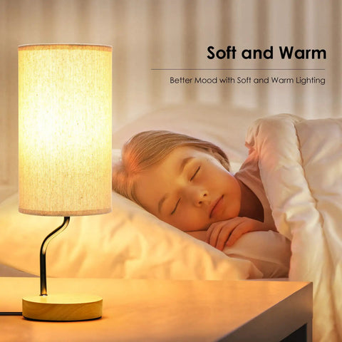 Upgraded Smart Bedside Table Lamp With Wireless Charger And USB Port for bedroom, lit on a wooden nightstand next to a sleeping child