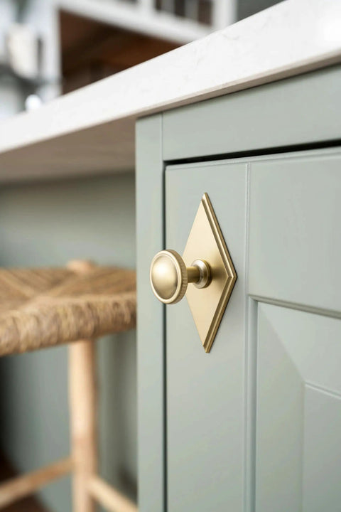 Slick Champagne Bronze Cabinet Knobs Pairing Fresh Rhombus Backplates With Fluted Dome Heads Brings Top Shelf Style To Your Kitchen Remodel Or Bathroom Refresh Alongside Three And A Half Inch Size Including A Set Of Six Go To Picks on a green cabinet.