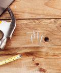 Double Headed Baseboard Screws For Solid Wood Trim And MDF Skirting on wooden surface with hammer and measuring tape