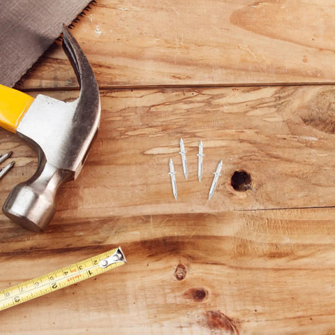 Double Headed Baseboard Screws For Solid Wood Trim And MDF Skirting on wooden surface with hammer and measuring tape