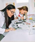 Lab scene with two women in white coats using a microscope and a Festfends Metal Test Tube Drying Rack For Lab Use.