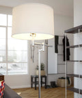 Theta Swing Arm Floor Lamp with Brushed Steel Finish and Drum Shade in modern living room by large window.