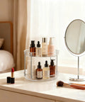 Two Pack Two Tier Clear Acrylic Lazy Susan Turntable Organizer holding skincare bottles on a vanity table next to a mirror.