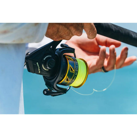 Angler holding Battle III Inshore Spinning Reel with HT-100 Front Drag, 12 lb max drag, all aluminum construction, black gold finish.